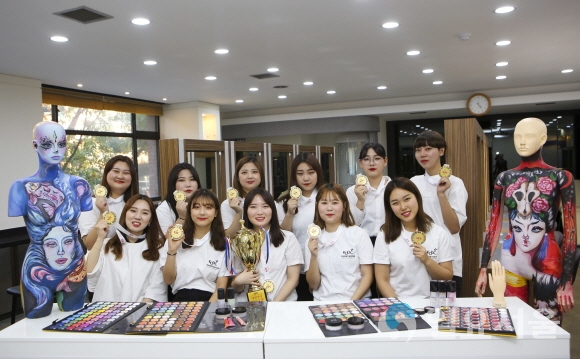 ‘제12회 한국미용기능경기대회(KOBC)’에서 우수한 성적으로 전원 수상한 학생들이 트로피와 메달을 보이며 활짝 웃고 있다. 사진=계명문화대