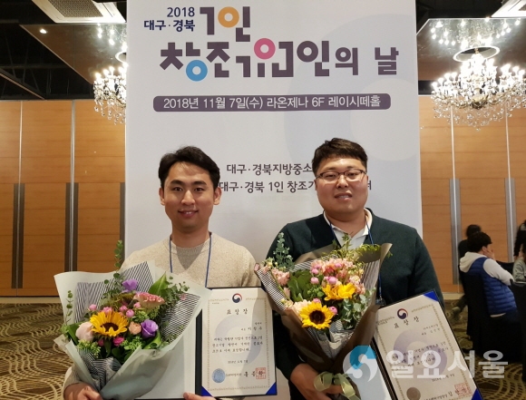‘2018 1인 창조기업의 날’행사에서 수상한 계명문화대학교 1인 창조 입주기업 대표들이 상장을 보이며 활짝 웃고 있다(좌측 엘앤비 이창우 대표, 우측 ㈜ 에스에스알 김진한 대표). 사진=계명문화대