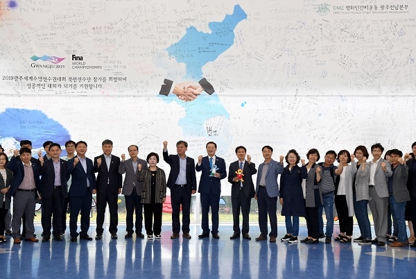 이용섭 광주광역시장이 27일 오후 시청 1층 시민홀에 남북평화와 2019광주세계수영선수권대회 북한 선수단 참가 등 염원을 담아 설치된 대형 현수막 앞에서 기념촬영을 하고 있다.(사진제공=광주광역시)