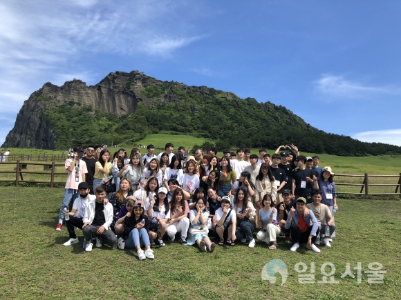 제주도 성산일출봉을 배경으로 기념촬영을 하고 있는 호산대 외국인 유학생들. 사진=호산대