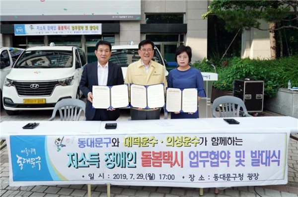 ▲ 동대문구가 29일(월) 구청 광장에서 진행한 ‘저소득 장애인 돌봄택시 지원 사업’ 발대식 및 업무협약식에서 유덕열 동대문구청장(가운데)과 문충석 대덕운수 대표(왼쪽), 김미애 의성운수 대표가 기념 촬영을 하고 있다.