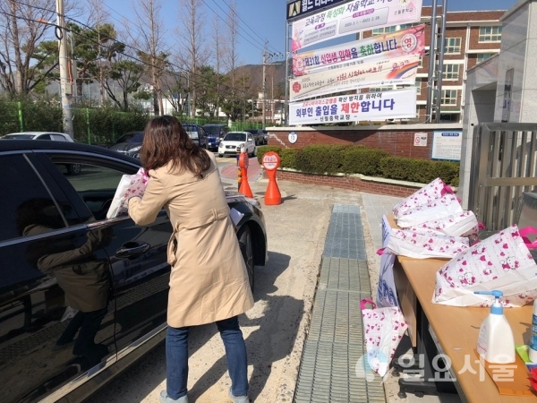 창원 신월중학교는 지난 20일 '코로나19'로 인한 개학연기로 아직 배부하지 못한 새학기 교과서를 도내 최초로 드라이브 스루 서비스(자동차탑승전달) 방식으로 학부모님께 전달했다. @ 창원 신월중학교 제공