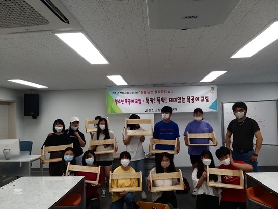 목공예교실에서 청소년들이 작접 만든 책꽂이를 들고 단체사진을 찍고 있다.