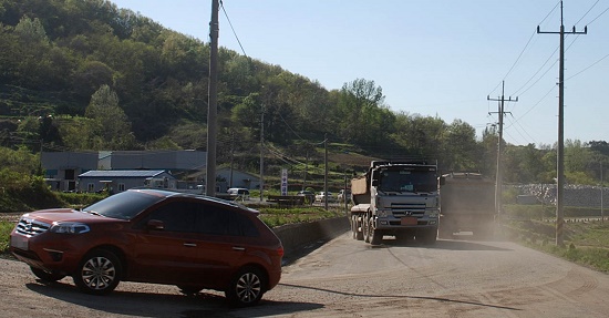 토석채취장의 토석을 운반하는 트럭들이 도로를 통행하면서 비산먼지를 일으키고 있다.  [뉴시스]