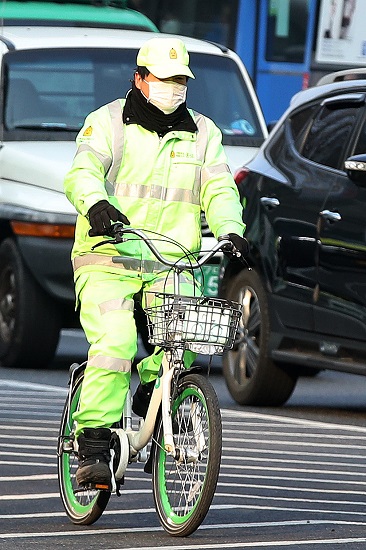 지난 12일 오전 서울 종로구 광화문 네거리에서 한 환경미화원이 미세먼지 마스크를 쓰고 자전거로 이동하고 있다. [뉴시스]