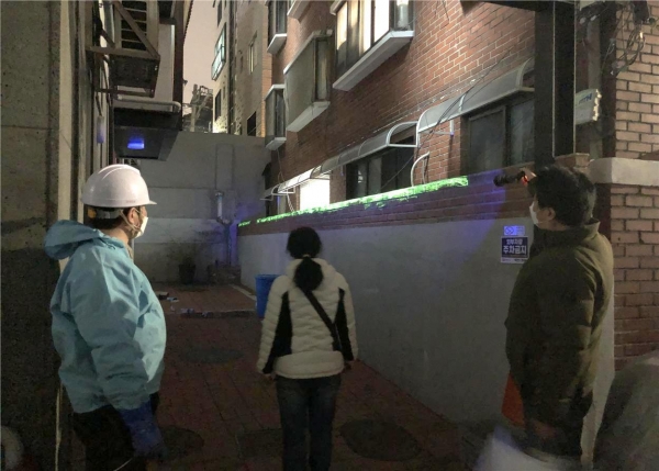 서대문구 관계자가 연희동 ‘스파이더범죄 예방마을’의 한 건물 담장 위에 도포된 형광물질을 특수 손전등으로 비추자 연두색 빛이 나타나고 있다