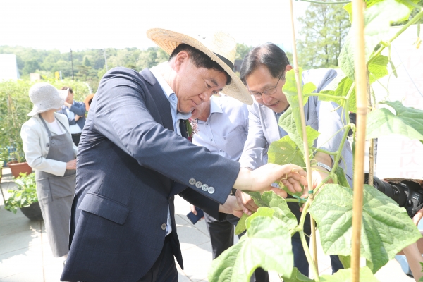 박준희 구청장이 박람회장 부스를 순회하며 친환경 도시농법으로 자란 수확물 직접 체험하고 있다