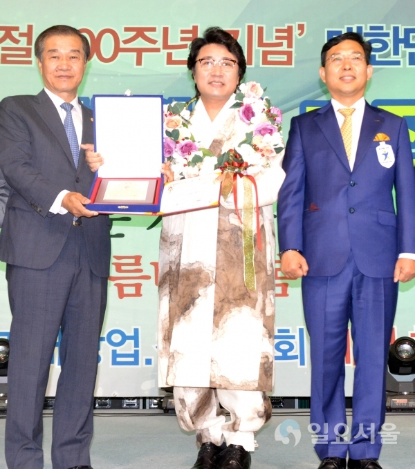 (가운데)김포시홍보대사 한한국 세계평화작가가 (왼쪽)황인무 시상총재와 (오른쪽)조영관 대표로부터 세계최고기록 인증서를 받고 있다