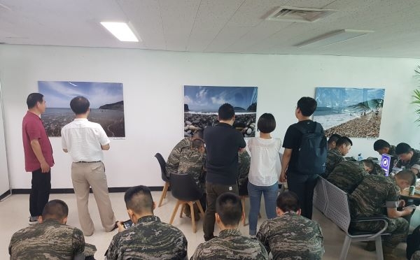 인천항연안여객터미널 2층 고객라운지에  설치된 옹진군 명소사진들을 보고 있는 관광객들