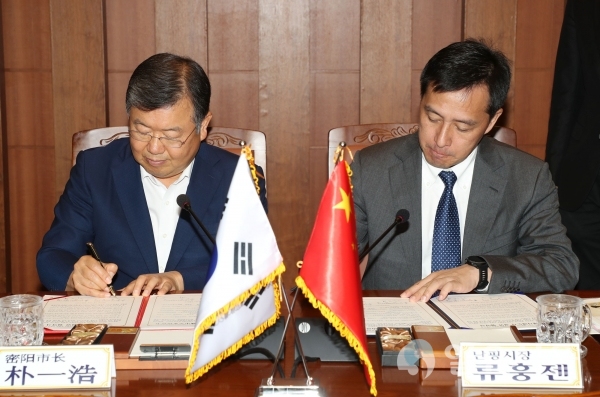 박일호 밀양시장(왼쪽)과 류훙젠 난핑시장(오른쪽)이 국매자매도시결연 협약서에 서명하고 있다.     © 밀양시 제공