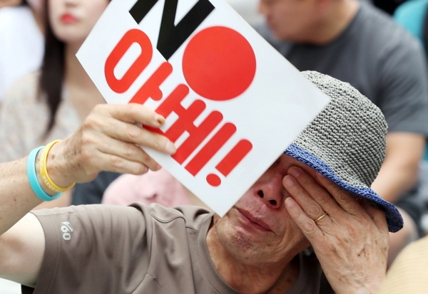 서울 종로구 구 일본대사관 앞에서 지난 21일 열린 일본군성노예제 문제 해결을 위한 제1401차 정기 수요시위에서 한 시민이 '노 아베' 손피켓을 들고 눈물을 닦고 있다. [뉴시스]