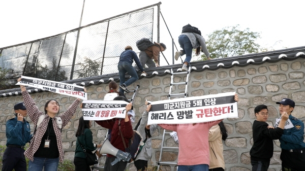 한국대학생진보연합이 18일 오후 서울 중구 주한 미국대사관저에서 방위비분담금 협상과 관련해 기습 농성을 하기 위해 담벼락을 넘고 있다. [뉴시스]