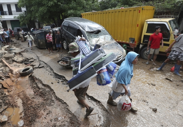인도네시아 자카르타 수도권에 새해 첫날 발생한 홍수로 약 30명이 숨진 가운데 지난 1월3일(현지시간) 자카르타 동쪽 브카시 마을 주민들이 홍수에 파손된 차량 주변을 지나고 있다. [뉴시스]