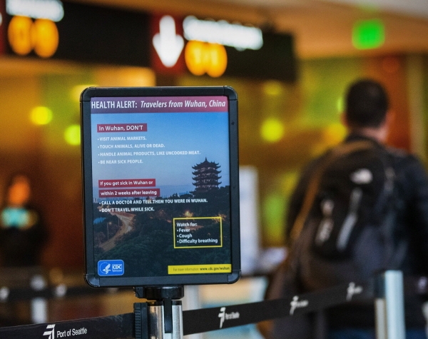 지난달 29일 미 워싱턴주 시애틀·터코마 국제공항에서 한 승객이 신종 코로나바이러스 감염증(우한 폐렴) 경고 문구를 지나쳐 걷고 있다. [뉴시스]