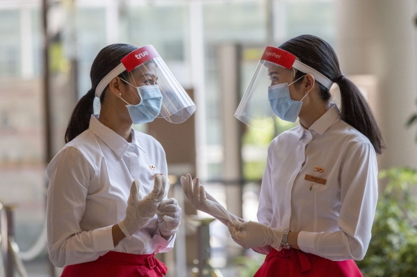 지난 14일 태국 방콕의 한 쇼핑몰에서 신종 코로나바이러스 감염증(코로나19) 예방을 위해 마스크와 페이스 실드를 착용한 직원들이 장갑을 착용하고 있다. [뉴시스]