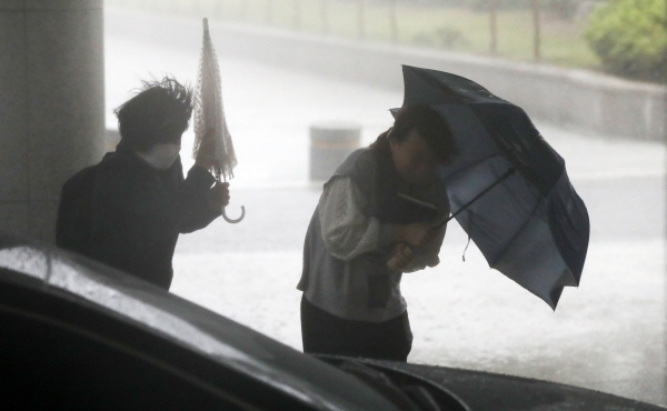 비가 내린 18일 오후 서울 서초구 서울고등검찰 인근에서 시민들이 비바람을 피하고 있다. [뉴시스]