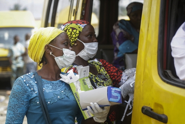 지난 3월27일 나이지리아 라고스의 한 버스 정류장에서 여성들이 신종 코로나바이러스 감염증 확산을 막기 위해 마스크와 장갑을 승객들에게 판매하고 있다. [뉴시스]