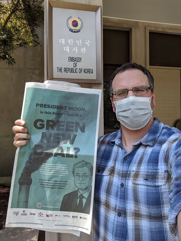 미국 환경단체 활동가가 워싱턴DC 주미한국대사관 앞에서 신문광고를 들고 항의하고 있다. [사진제공=Oil Change International]