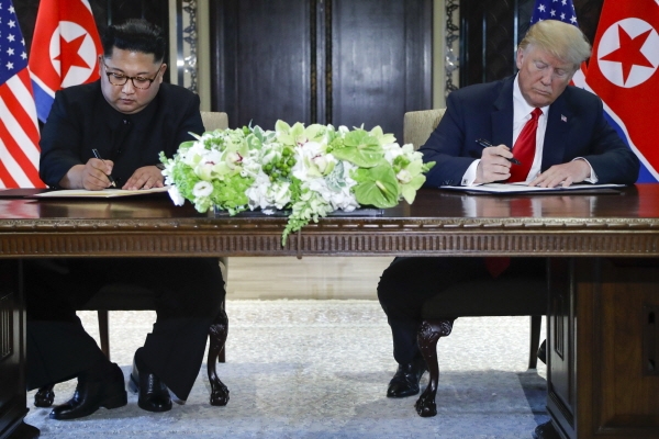 김정은 북한 국무위원장(왼쪽)과 도널드 트럼프 미 대통령이 12일 싱가포르 카펠라 호텔에서 사상 첫 북미 정상회담을 마친 뒤 합의문에 서명하고 있다. 2018.6.12[뉴시스]
