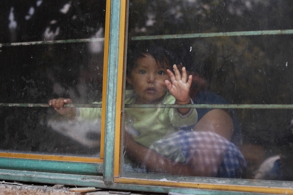 멕시코의 윅스퀼루칸주 피에드라 그란데의 고원지역에까지 코로나19가 확산되면서 한 주택의 창문안에서  배급음식과 생필품을 기다리며 밖을 내다보고 있는 아이. [뉴시스]