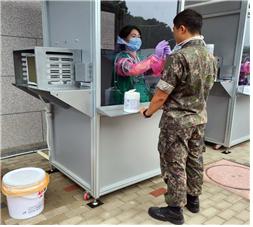 국군수도병원 간호장교가 검체채취부스를 활용하여 환자의 검체를 채취하고 있다. [사진=국방부 제공]