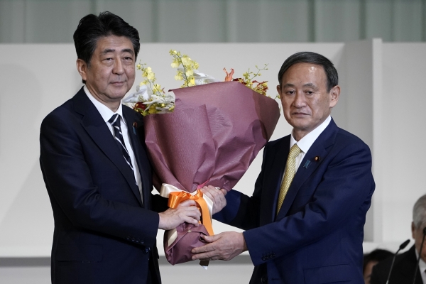 아베 신조(왼쪽) 일본 총리가 14일 도쿄의 한 호텔에서 열린 자민당 총재 선거에서 총재로 선출된 스가 요시히데 관방장관에게 꽃다발을 건네며 축하하고 있다. 스가 관방장관은 이날 열린 총재 선거에서 총재로 선출돼 사실상 새 총리로 확정됐다. 2020.09.14. [뉴시스]