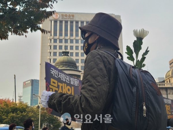 박정희 서거 41주기 추모 행진에 참여한 시민이 추모 국화와 시위 피켓을 들고 있다. [사진=신수정 기자]
