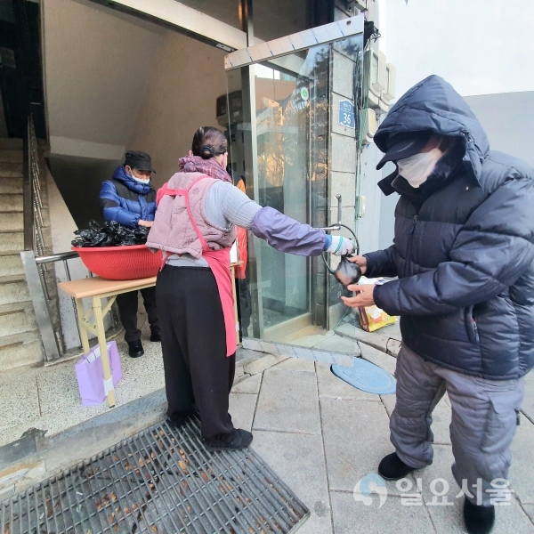 무료급식소 앞에서 주먹밥을 나눠주고 있다 [사진=김혜진 기자]