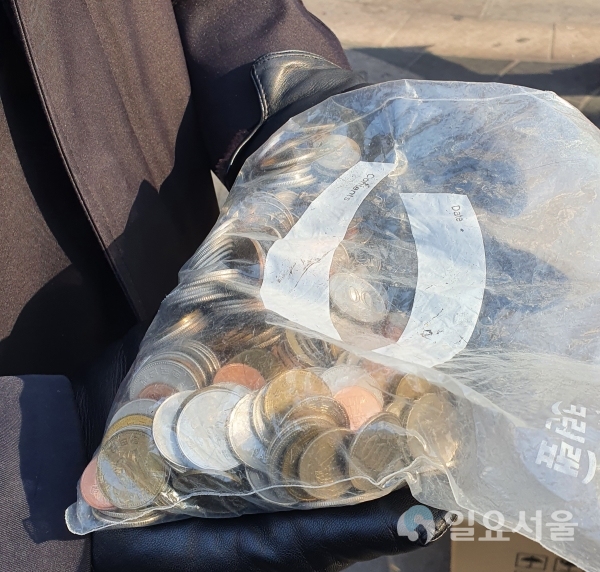한 기부자가 동전을 수북하게 담은 지퍼백을 자원봉사자에게 전달했다. [사진=김혜진 기자]