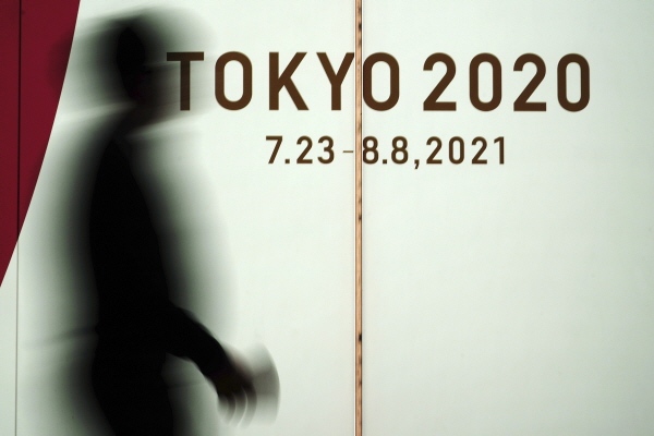 지난 17일 일본 도쿄에서 코로나19 확산을 막기 위해 마스크를 쓴 한 남성이 2020 도쿄 올림픽 광고판 앞을 지나고 있다. [뉴시스]