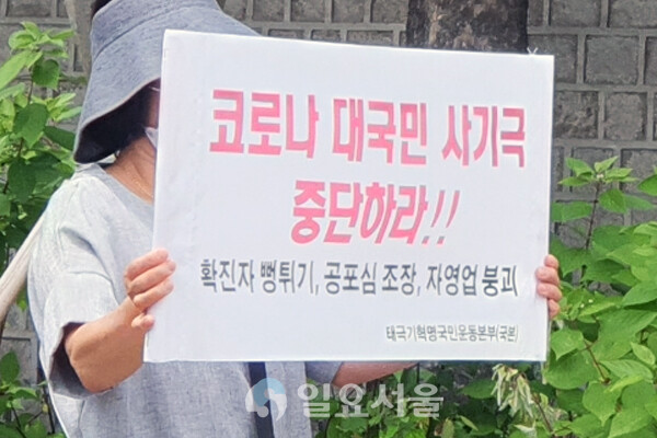 태극기혁명국민운동본부 관계자가 코로나19는 정부의 對국민 사기극이라는 피켓을 들고 시위하고 있다. [이창환 기자]